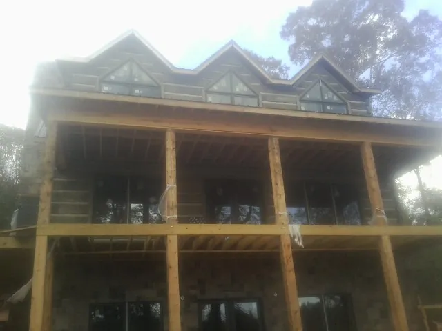 Dormers and porch framing on a large log home under construction — Roof Coating work by our crew in Cedarbluff