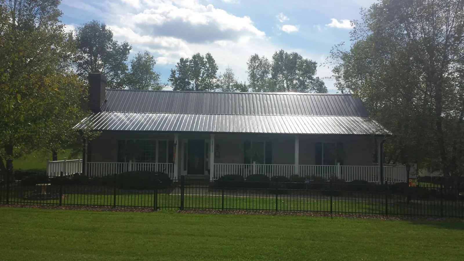 Gray metal roof on a brick ranch with a full width front porch — Gutter Guard Installation work by our crew in Cedarbluff